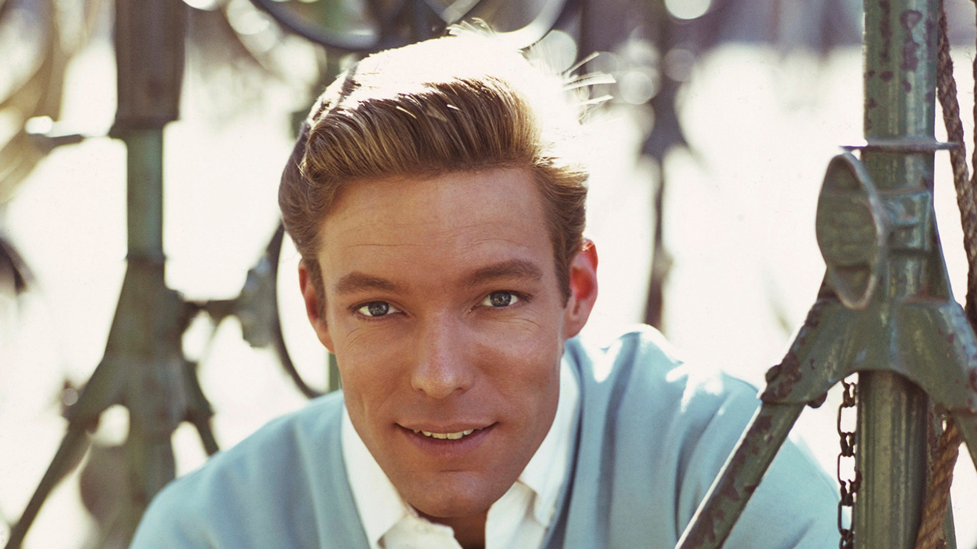Richard Chamberlain wears blue sweater and white shirt.
