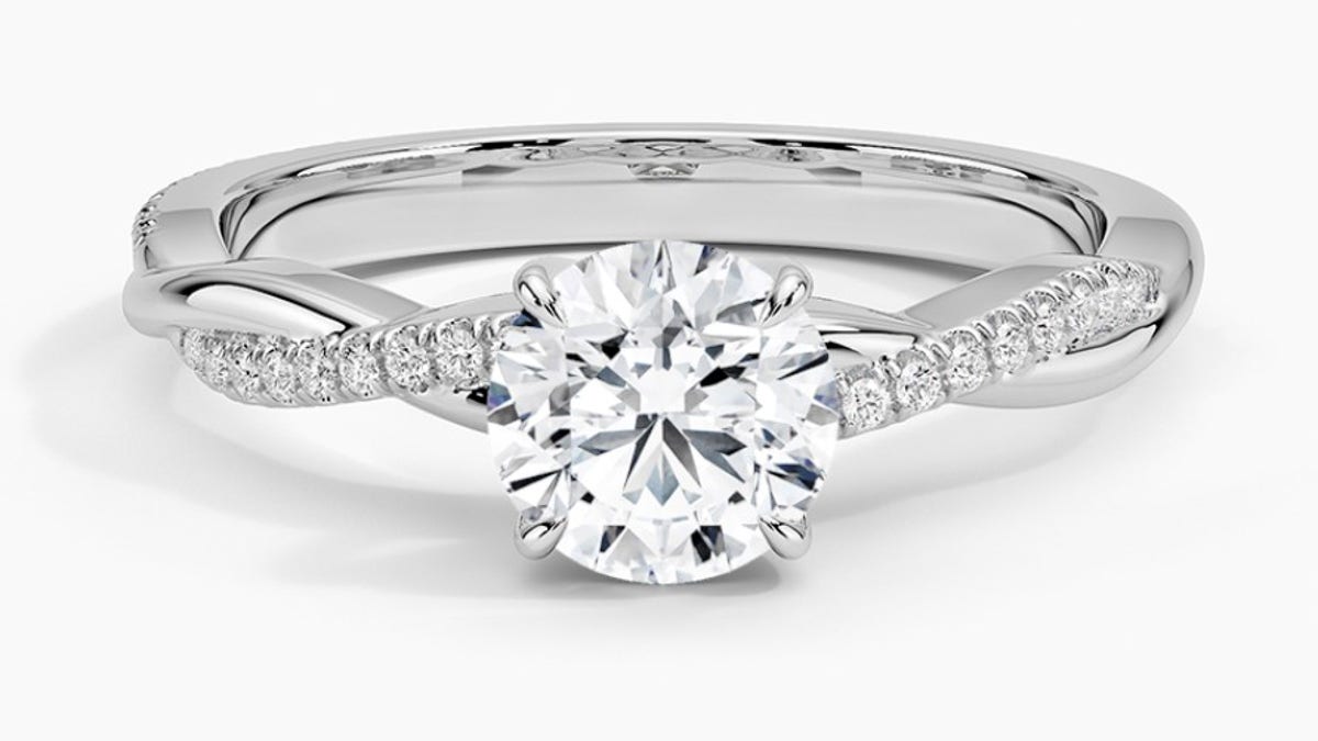 This elegant solitaire ring showcases a delicate platinum twisted vine band adorned with pavé diamonds. 