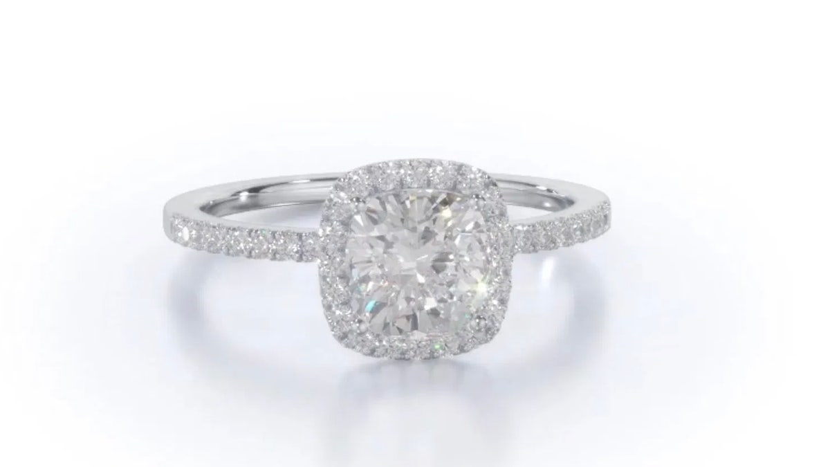 This With Clarity ring features a cushion-cut center diamond surrounded by a halo of smaller diamonds.