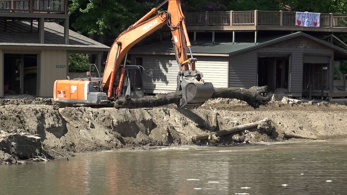 Excavator being used to pick up logs and debris caused by Hurricane Helene
