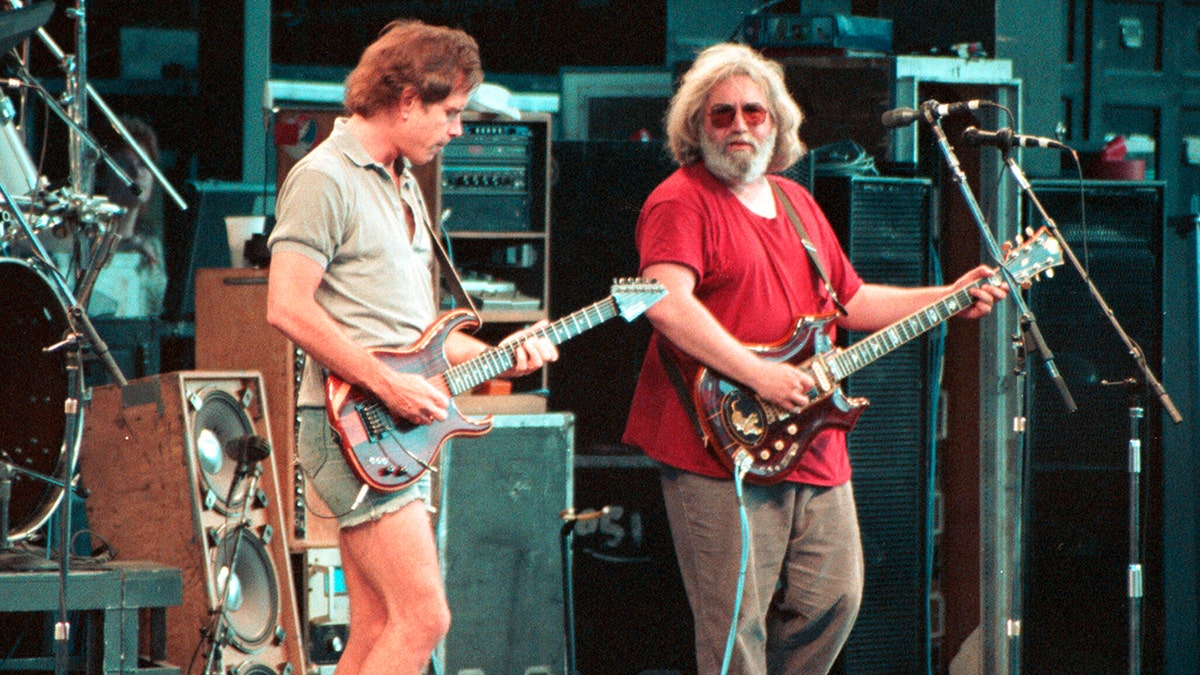 Bob Weir and Jerry Garcia playing guitar on stage together.
