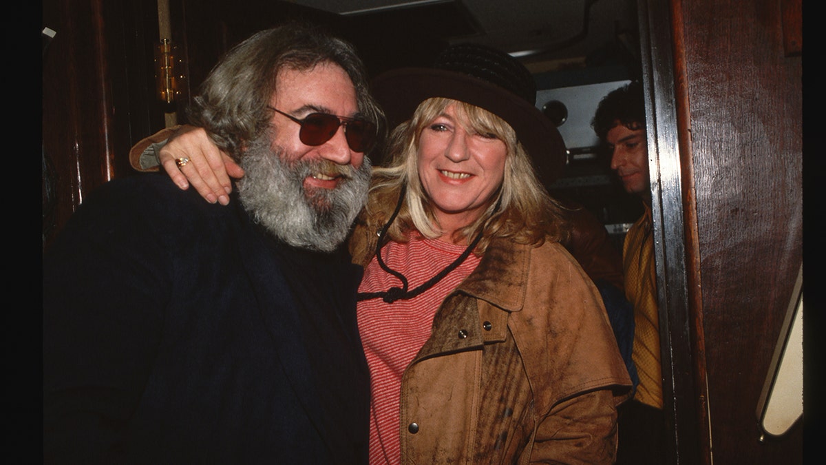 Jerry Garcia smiling and being embraced by Christine McVie.