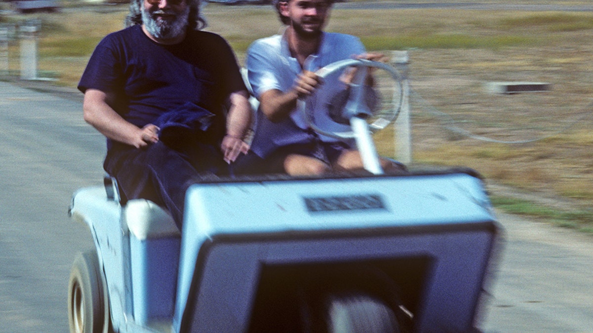 Jerry Garcia on a golf cart smiling.