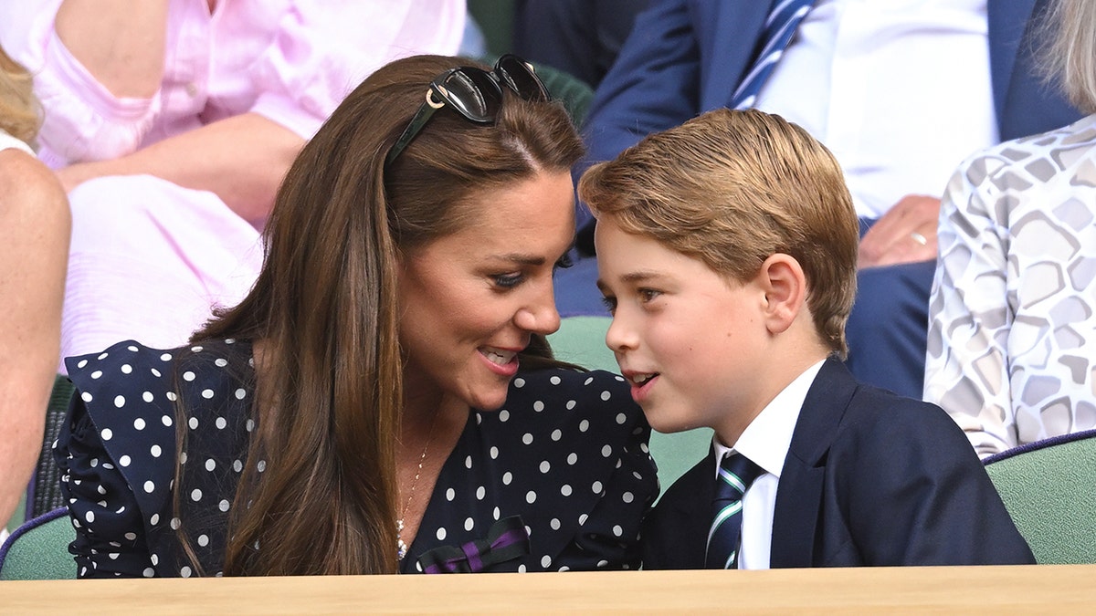 Kate Middleton in a polka dot dress chatting with Prince George in a suit.