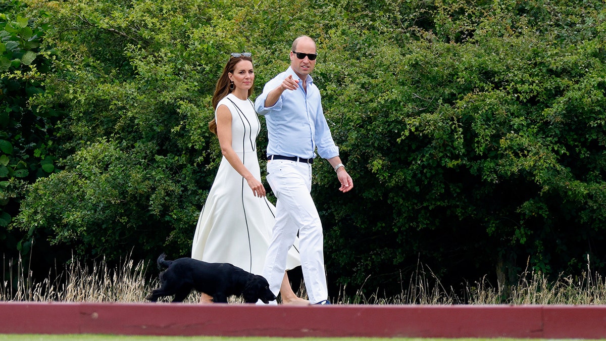 Kate Middleton and Prince William walking together outdoors dressed.