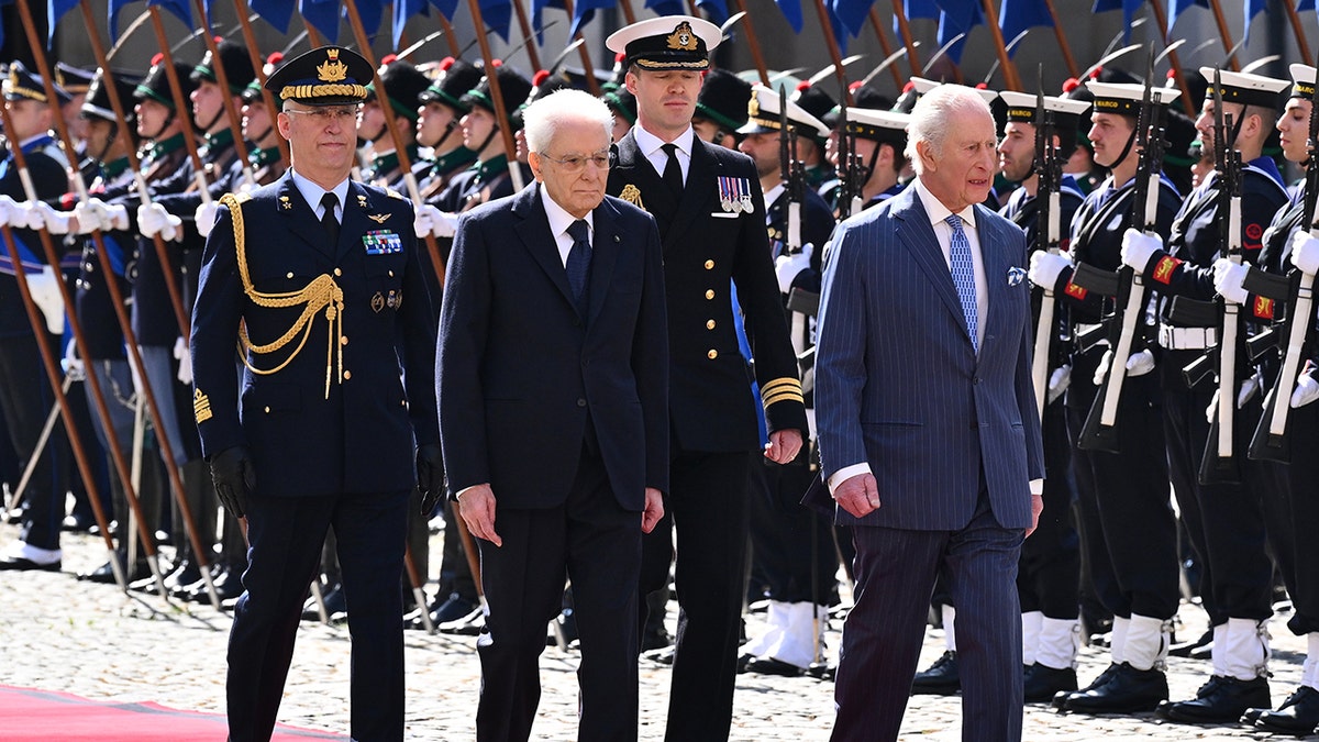 King Charles walks with a group of men with soldiers outside Italy.