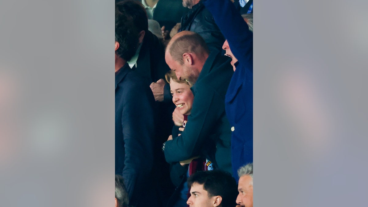 Prince William laughing and holding onto a smiling Prince George