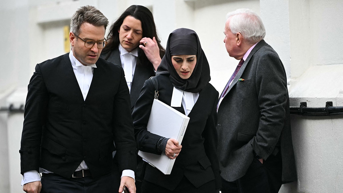 Prince Harry's lawyer looks down at his formal black and white outfit.