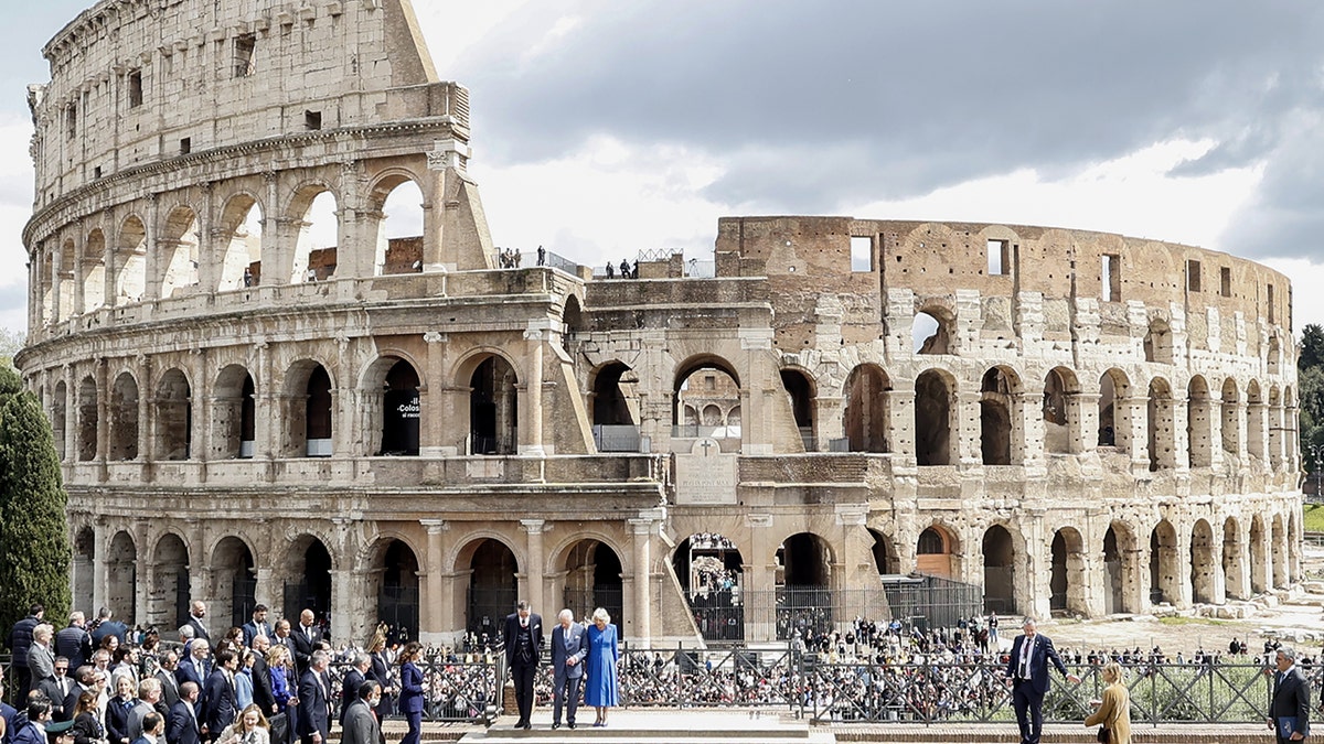 King Charles and Queen Camilla stand together in front of the Roman crowd.
