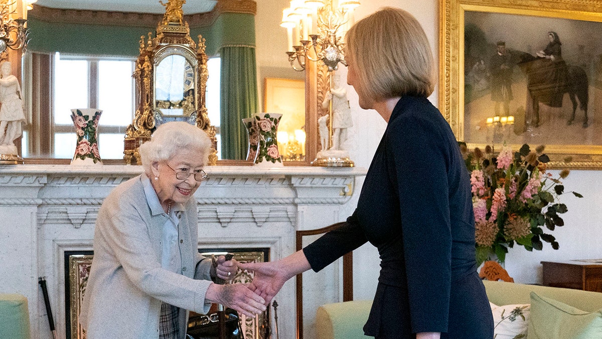 Queen Elizabeth smiling and shaking Liz Truss' hand.