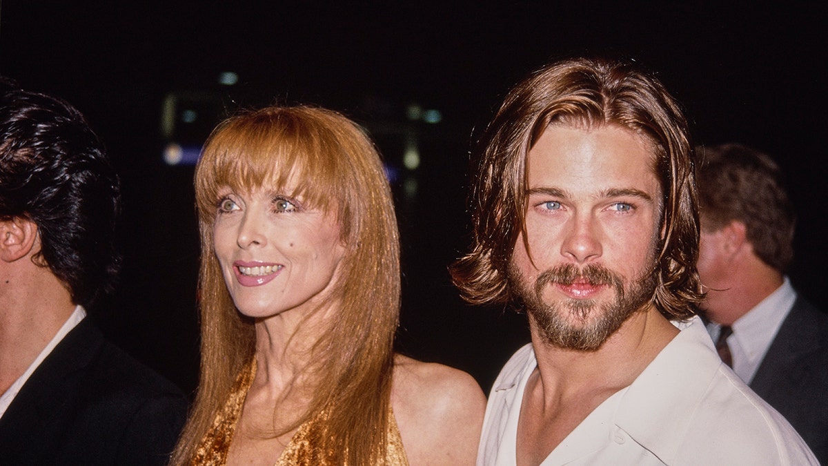 Tina Louise smiling next to Brad Pitt in a white shirt.