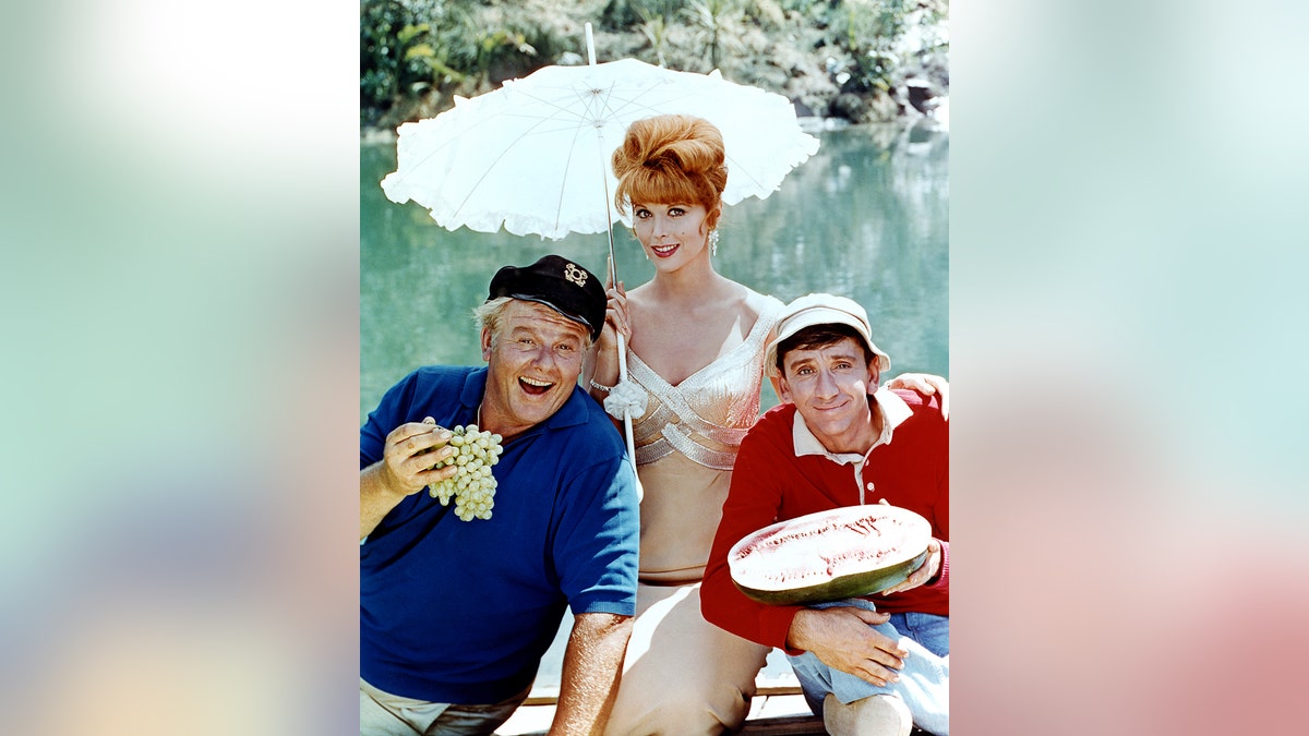 Tina Louise with two of her "Gilligan's Island" castmates as they smile and pose in costume outdoors.