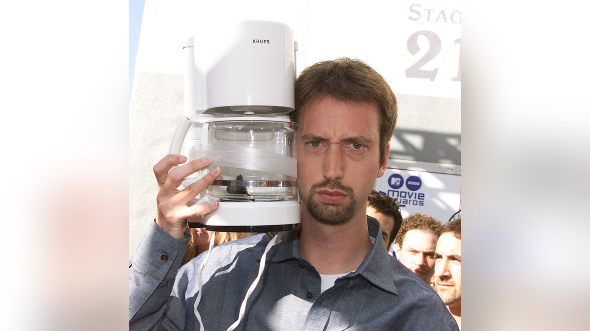 Tom Green holding a coffeemaker.