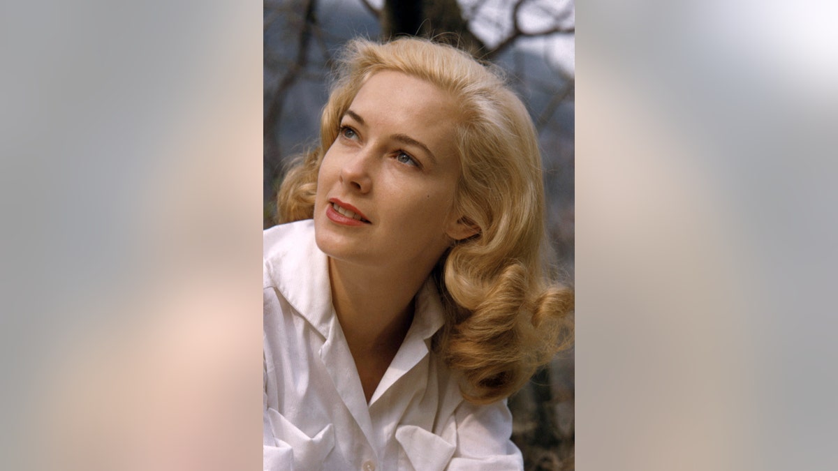 A close-up of Vera Miles looking to the side wearing a white collared shirt.