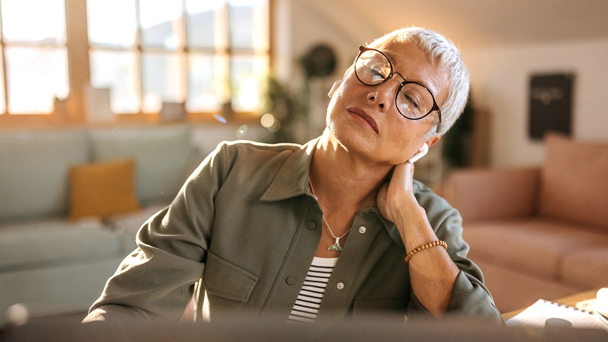 woman experiencing neck pain while working from home
