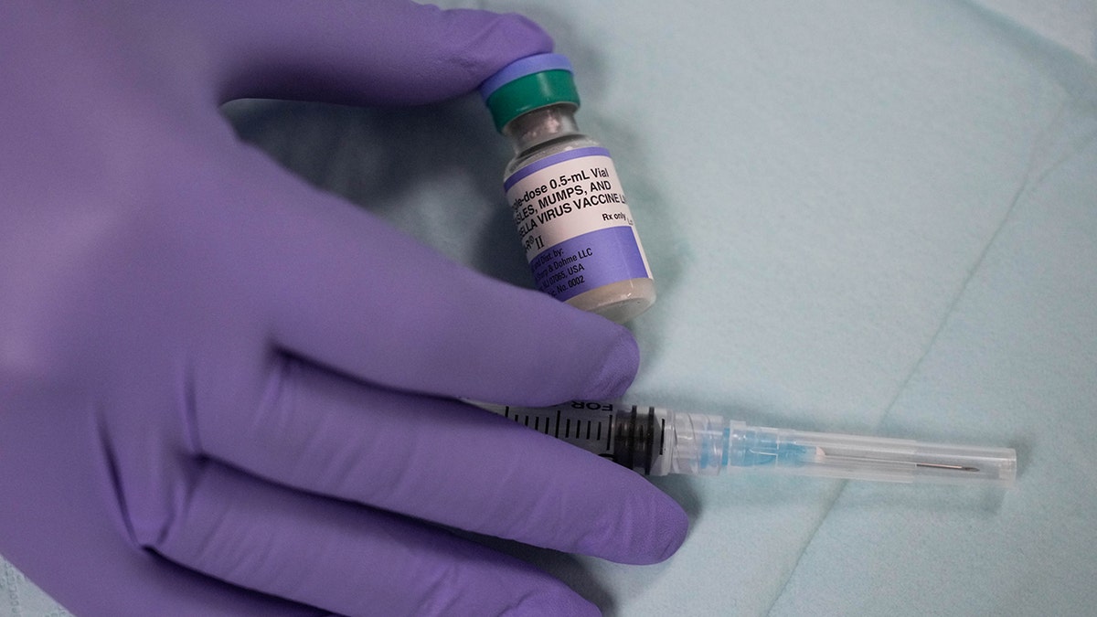 Closeup shot of a gloved hand holding the MMR vaccine