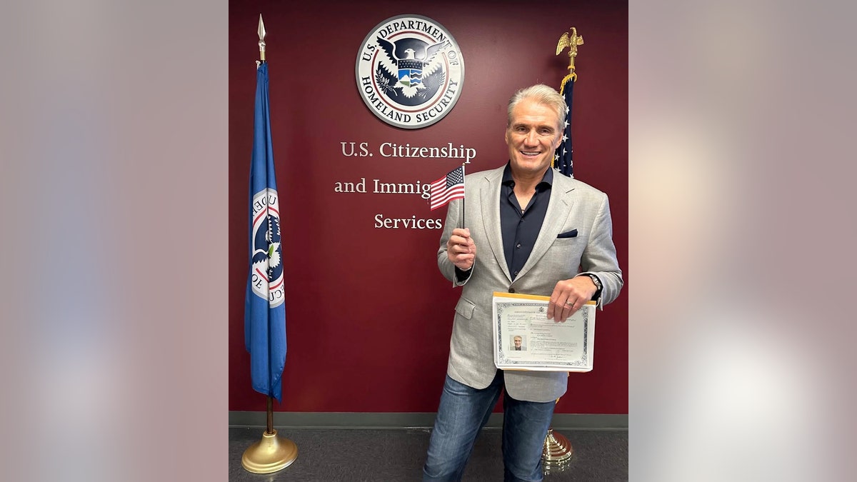 Dolph Lundgren holding his citizenship and waving a flag.