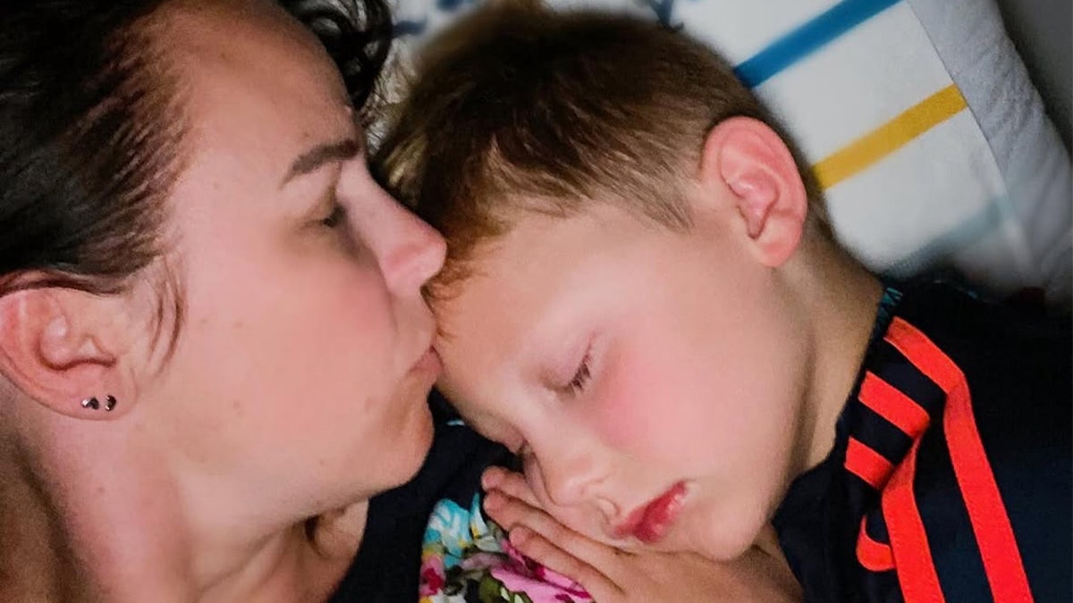 Oliver sleeping with his mother kissing his forehead