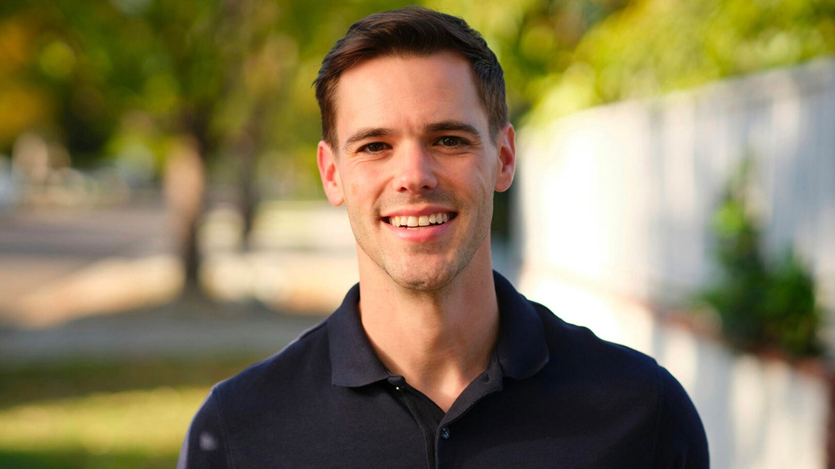 Jake Rakov, smiling outdoors in a dark polo shirt