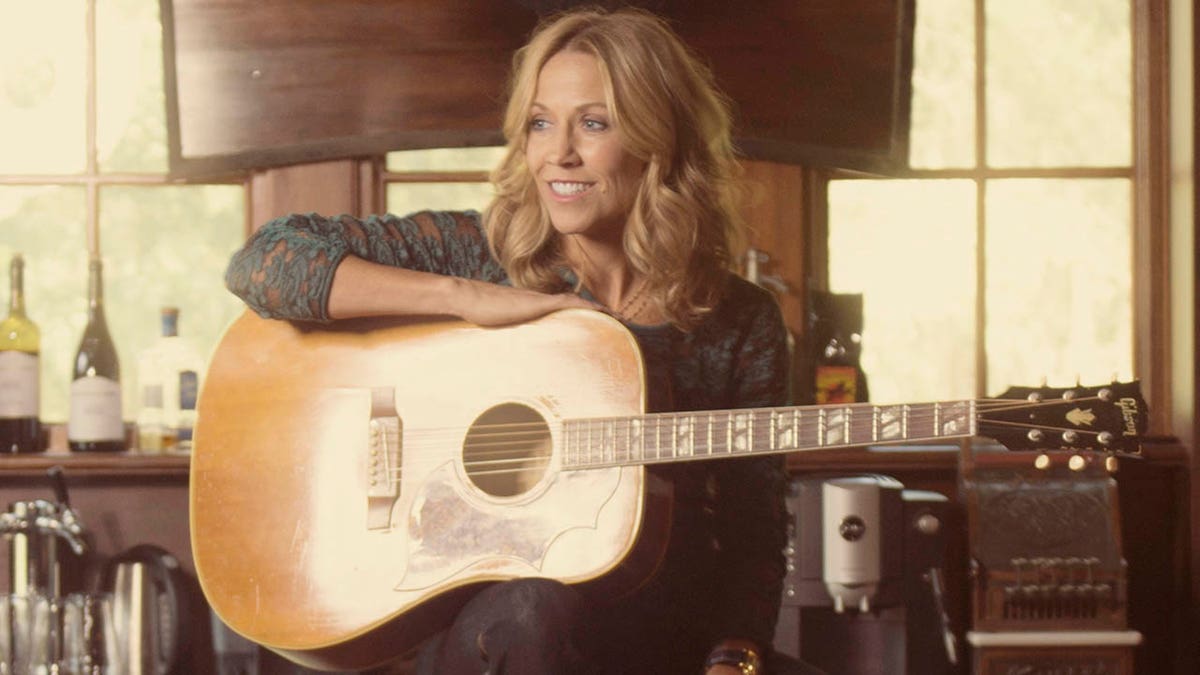 sheryl crow holding a guitar sitting in her saloon at her farm