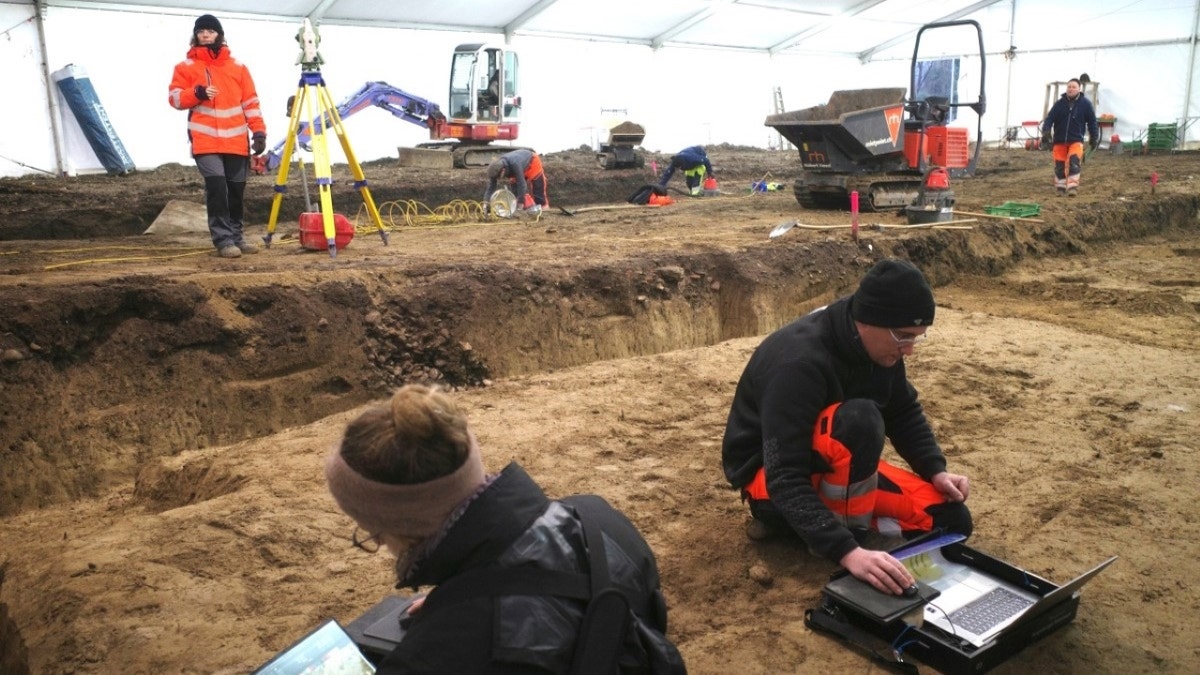 Archaeologists digging holes at excavation site