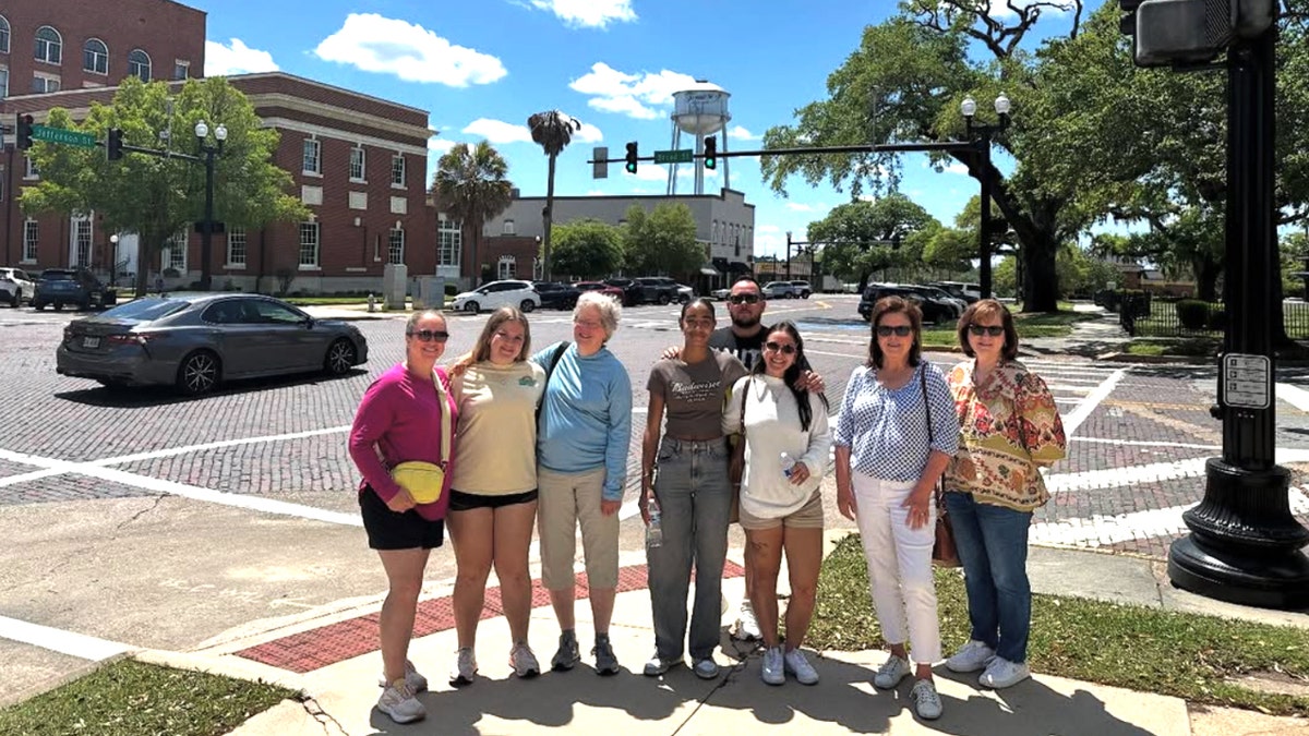 Nine group airs for a photograph successful downtown Thomasville, Georgia, pinch nan town's h2o building successful nan background.