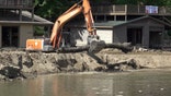 Excavator being used to pick up logs and debris caused by Hurricane Helene