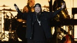 Jelly Roll on stage holding up both arms