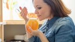 A woman smells a jar containing natural organic honey.