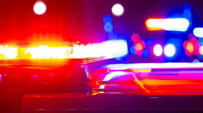 Close-up of flashing red, blue and yellow emergency lights on police vehicles at night.