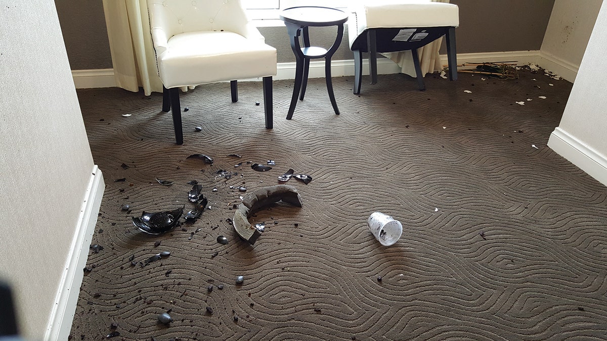 A broken vase on the floor in hotel room