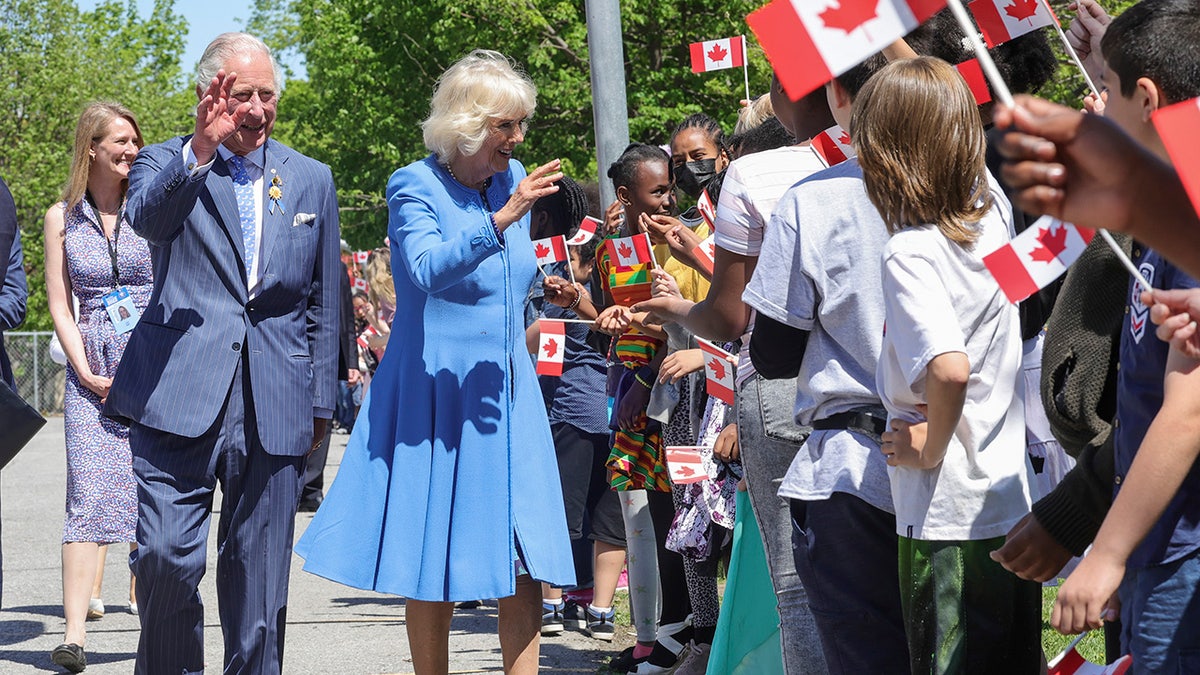 King Charles and Queen Camilla waving to people outside in Canada.