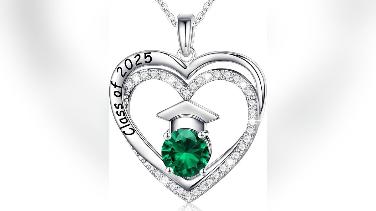 A necklace featuring a graduation cap cradling the sparkling birthstone of your choice, surrounded by a heart engraved with ‘Class of 2025.’