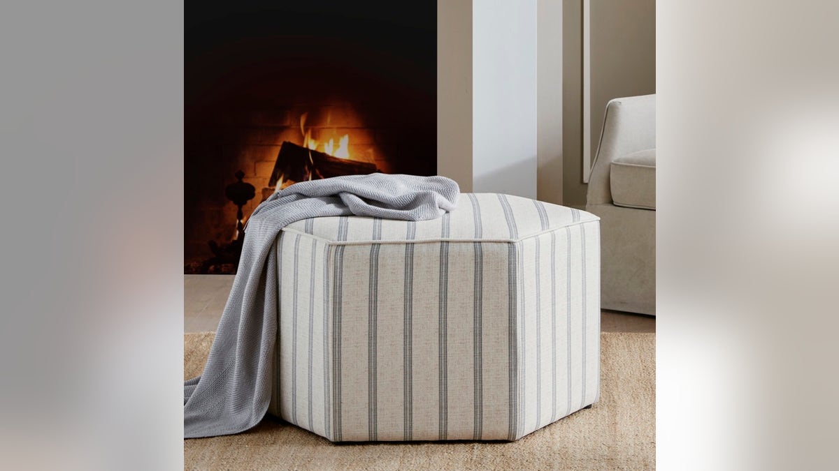 A blue and white Martha Stewart Ellen Cocktail Ottoman in front of a fireplace