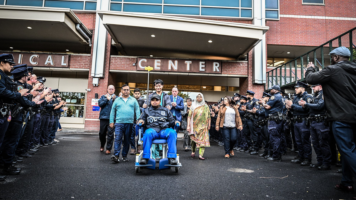 NYPD officer Chowdhury Nafees leaves the hospital in a wheelchair as fellow officers offer their support.