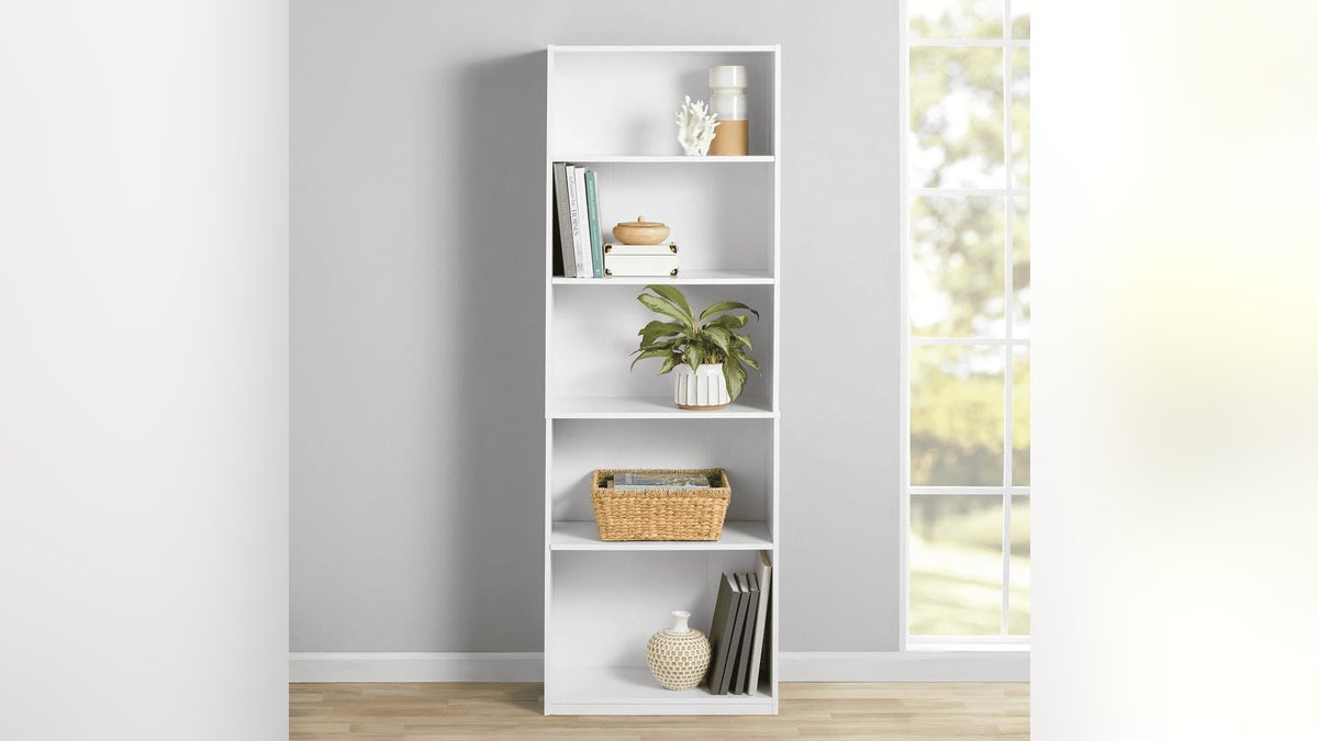 A small white bookcase on a light colored floor next to a window