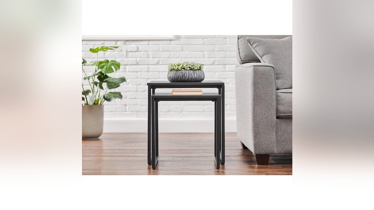 Two nesting side tables next to a plant and grey couch