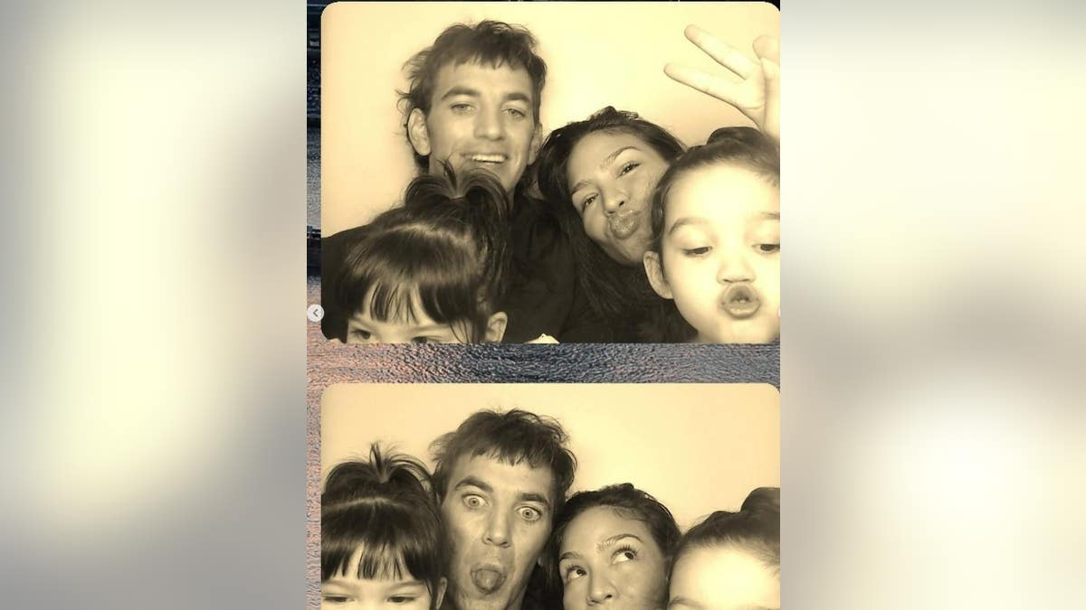 Cassie and Alex Fine and their daughters posing in a photo booth