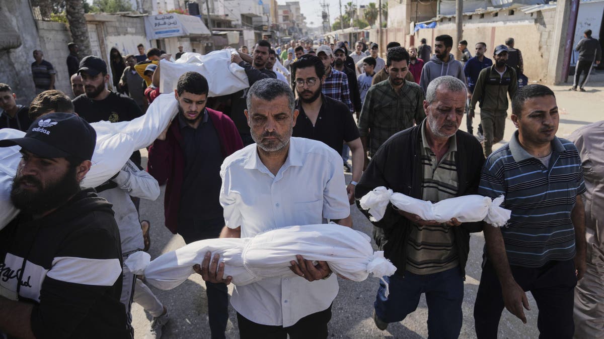 Palestinian man carries a wrapped body