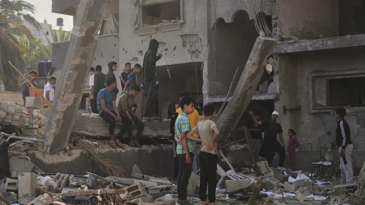 Children look at a destroyed building