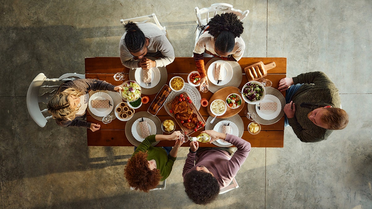 A bird's eye view shows three men and three women eating together at a table.