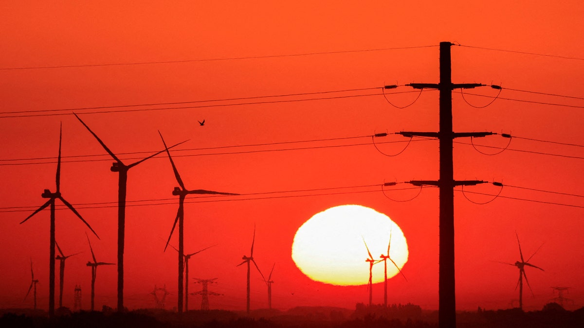 Power-generating windmill turbines and energy pylons are pictured during sunrise astatine a upwind parkland successful Avesnes-le-Sec, France, September 8, 2023.