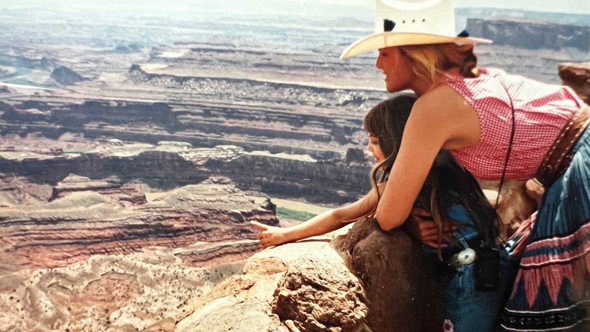 Christie Brinkley holding her daughter Alexa Ray and looking at mountains.