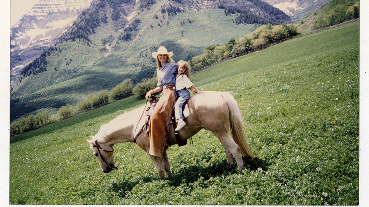 A snapshot of Christie Brinkley writing on horseback with her daughter on a mountain.