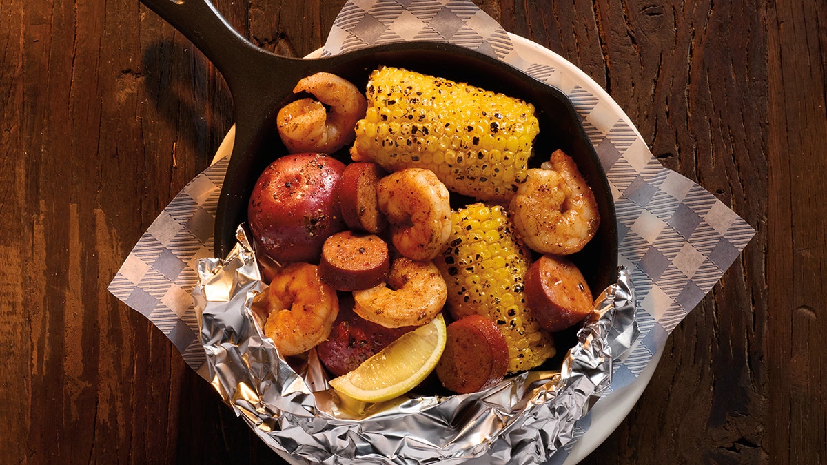 Cracker Barrel's Campfire Shrimp Skillet is shown on a wooden table.