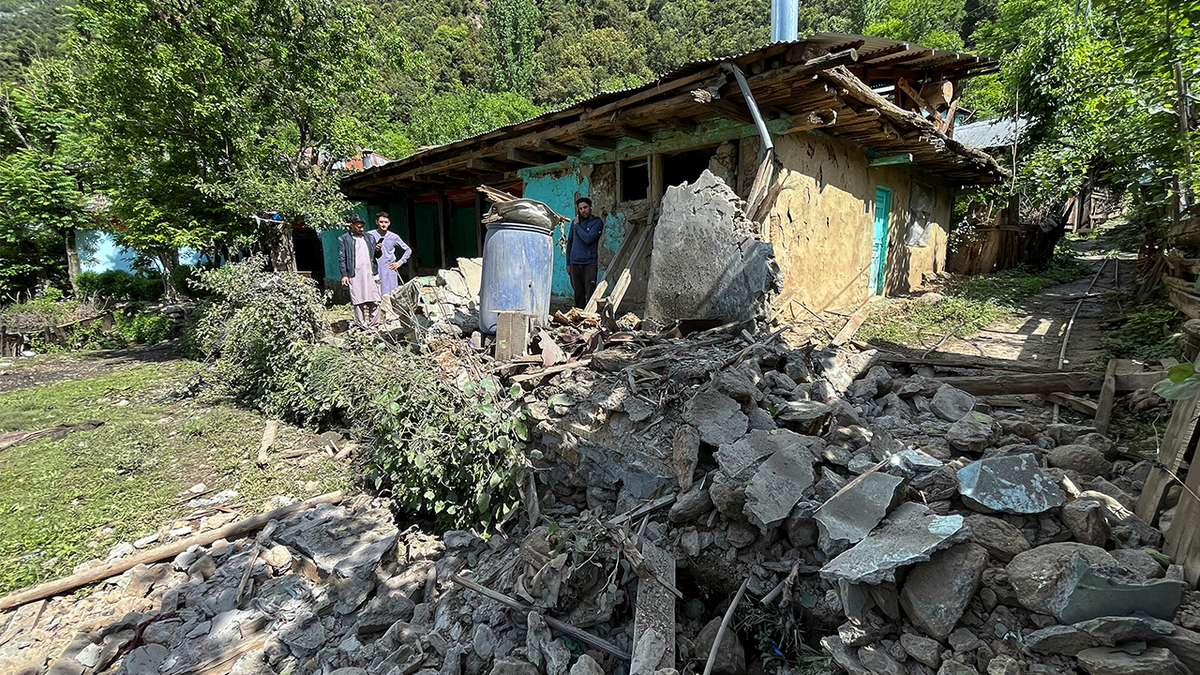 Villagers examine damages to a house caused by overnight Indian shelling