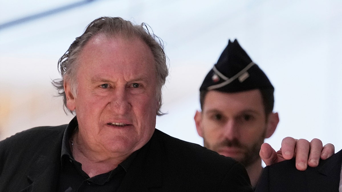 Gerard Depardieu with a guard behind him