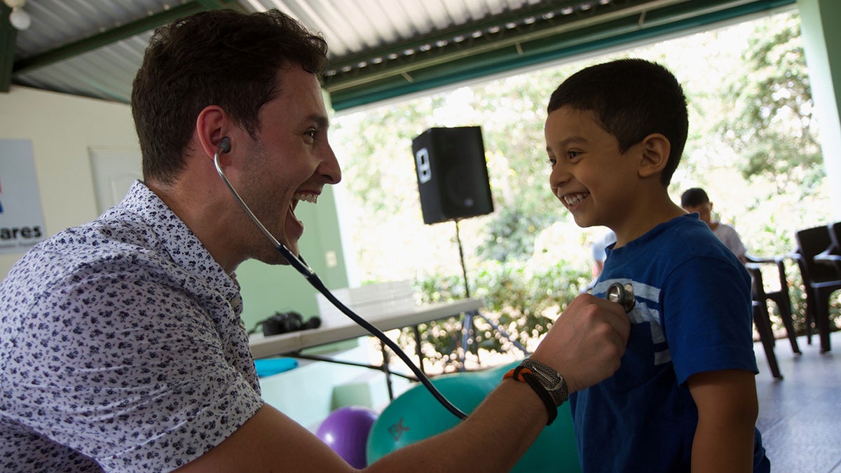 Dr. Mikhail Varshavski holds stethoscope to young boy's chest