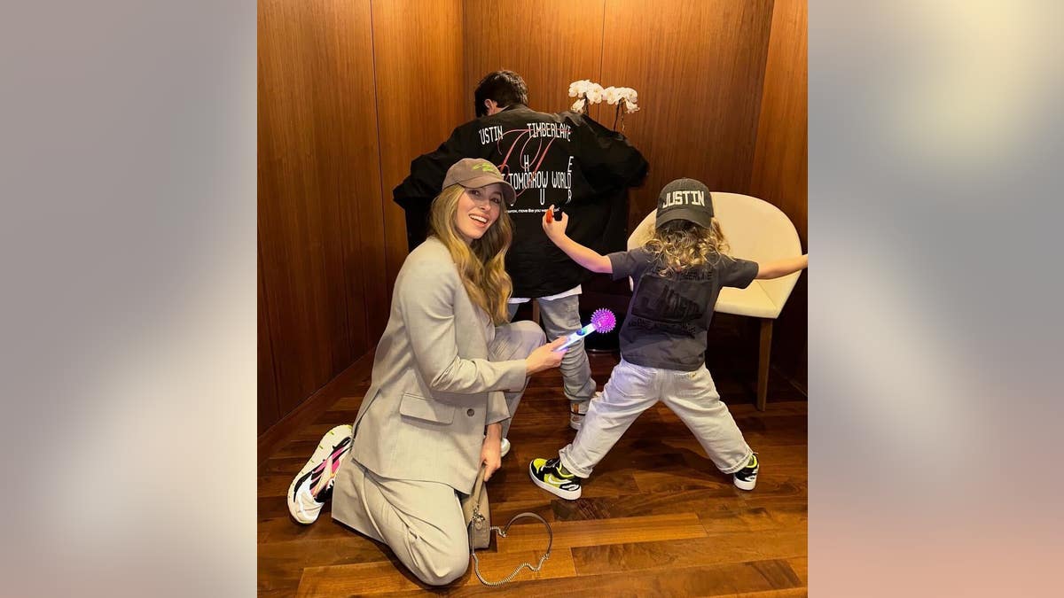 jessica biel posing with her kids who have their backs to the camera while wearing justin timberlake merchandise