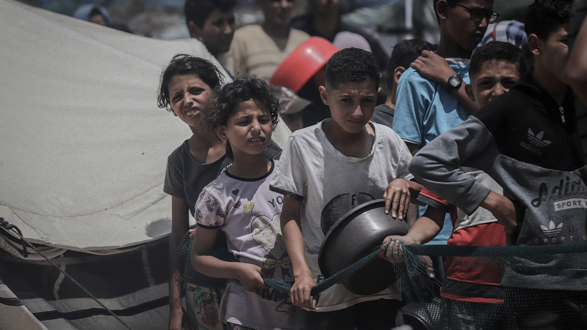 Displaced Palestinian children wait to receive a free meal from a charity food distribution center in Gaza City, northern Gaza, on Tuesday, May 27, 2025.